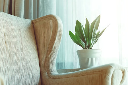 This image showcases a cozy armchair beside a bright window, featuring a lush potted plant that brings warmth and tranquility into the space.の写真素材