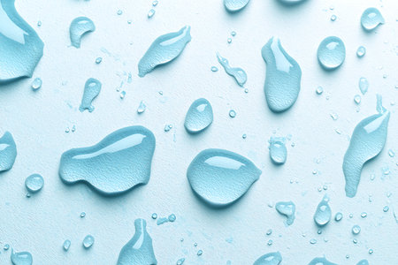 A captivating close-up image showcasing various water droplets on a smooth blue surface, highlighting beauty and purity in nature's design.の写真素材