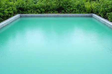 A tranquil scene of turquoise water surface, surrounded by vibrant green foliage. Ideal for nature, relaxation, or spa-themed projects.の写真素材