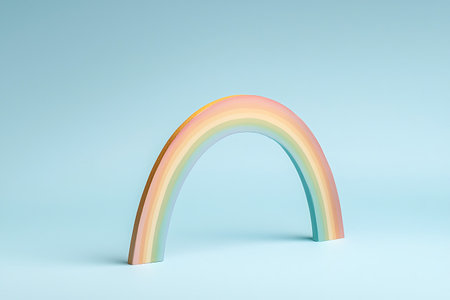 This colorful arch-shaped rainbow sculpture stands against a light blue backdrop, adding a playful touch to any creative space, perfect for artistic displays and childhood joy.の写真素材