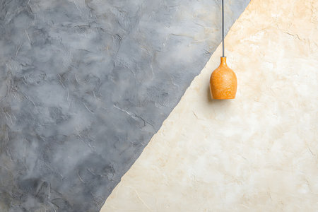 This artistic interior image features a beautifully textured wall split into gray and beige sections, with a stylish orange vase pendant light that enhances a cozy atmosphere.の写真素材