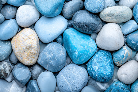 A close-up view of smooth blue pebbles and rocks creates a serene and colorful background suitable for various design projects and nature themes.の写真素材