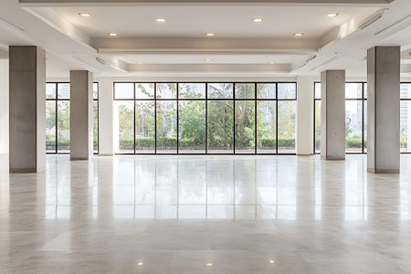 This spacious indoor space features large windows allowing ample natural light and beautiful views of lush greenery, perfect for various events or renovations.の写真素材