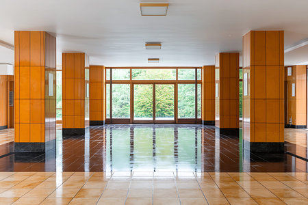 Bright and airy interior space featuring wooden columns and large windows that provide a view of lush greenery. Perfect for showcasing modern design.の写真素材