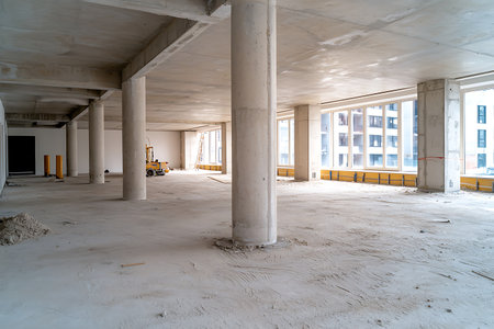 Bright and spacious empty commercial area under construction, featuring concrete columns and large windows, ideal for renovation and design projects.の写真素材