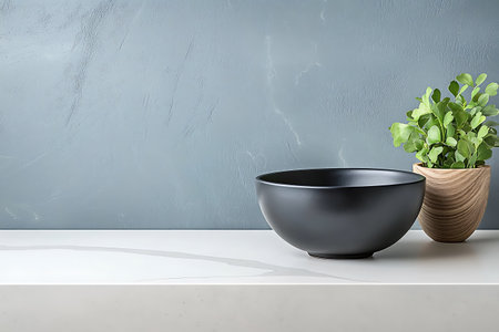 A stylish black bowl sits next to a green plant in a wooden pot, creating a serene and modern kitchen ambiance. The minimalist design highlights beautiful textures.の写真素材