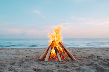 A captivating view of a warm bonfire on a serene beach at dusk, surrounded by soft sand and gentle...