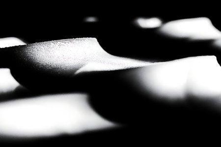 This captivating black and white image features an abstract display of light and shadows on smooth...