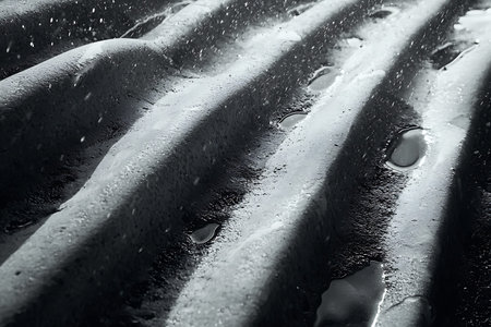 Captivating close-up of a wet textured surface highlighted by water droplets, showcasing dramatic...