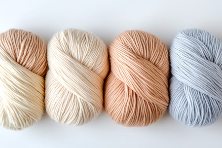 A collection of soft yarn bundles in beige, cream, peach, and light blue ideal for crafting and...