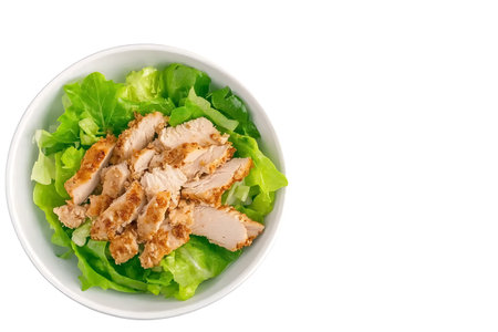 Fresh green lettuce tops a bowl featuring succulent slices of grilled chicken, a perfect healthy meal option packed with protein and flavor.の写真素材