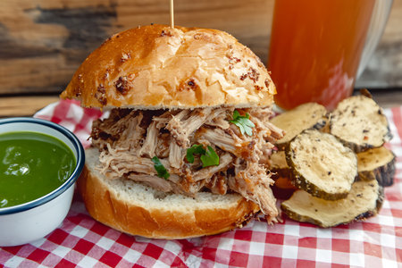 A fresh and tempting pulled pork sandwich served on a flaky bun, accompanied by crispy potatoes and...