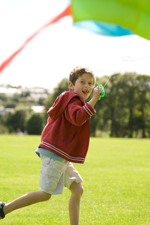 Boy running and laughing with a kiteの写真素材