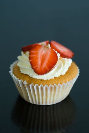 Cupcake decorated with strawberries and a swirl of creamの写真素材