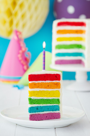 Rainbow cake decorated with a single candleの写真素材