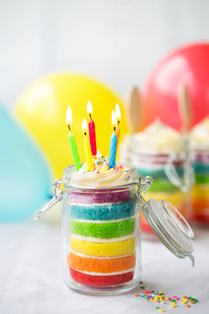 Rainbow layer cake in a jar with birthday candlesの写真素材