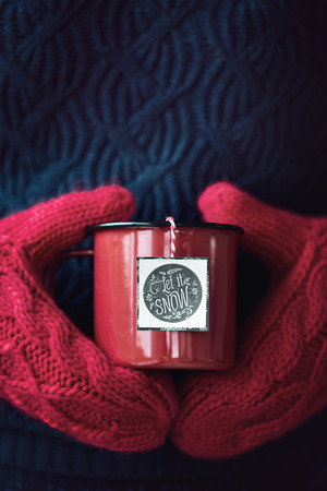 Mug of tea held in woollen mittensの写真素材