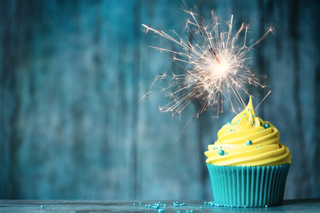 Cupcake with yellow buttercream and a sparklerの写真素材