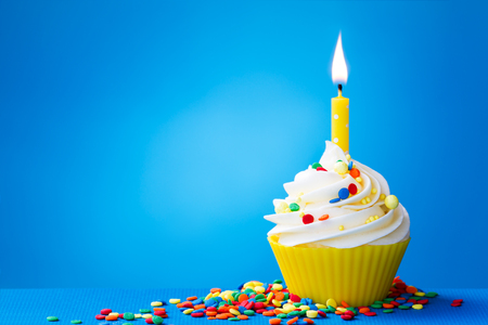 Birthday cupcake with a single yellow candleの写真素材