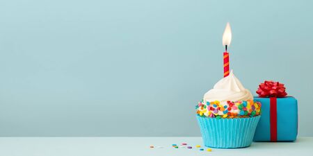 Birthday cupcake with candle and gift boxの写真素材