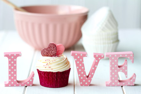 Cupcake decorated with fondant hearts with mixing bowl and love signの写真素材