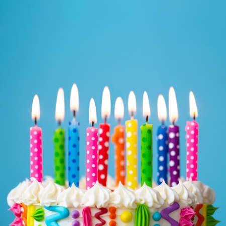 Colorful birthday cake with rainbow colored candlesの写真素材