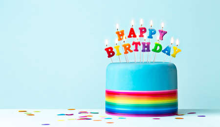 Colorful rainbow birthday cake with rainbow ribbon and rainbow birthday candlesの写真素材