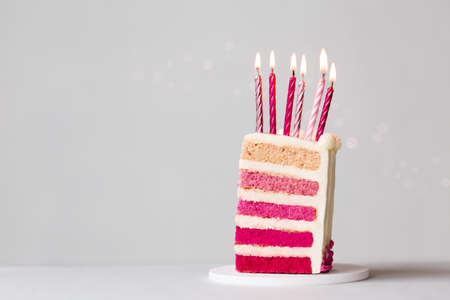Slice of pink ombre birthday cake with six pink birthday candles to celebrate a birthdayの写真素材