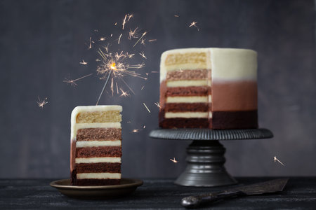 Chocolate ombre birthday cake with slice of birthday cake decorated with a celebration sparkler