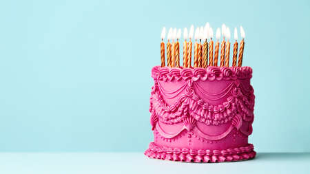 Fancy pink birthday cake with vintage style buttercream frills and ruffles and gold birthday candles against a blue backgroundの写真素材