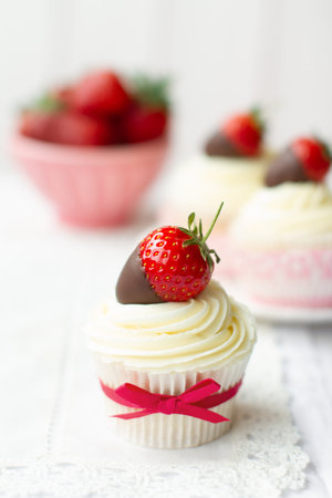 Cupcakes decorated with whipped cream and chocolate dipped strawberriesの写真素材