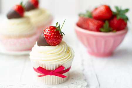 Strawberries and cream cupcakes served with fresh strawberries dipped in chocolateの写真素材