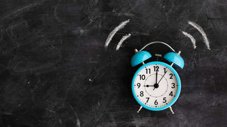 Twin bell alarm clock ringing against a chalkboard with copy space to sideの写真素材