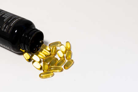 gel capsules with omega 3 spill from the bottleの写真素材