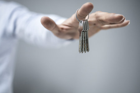 man in a shirt holding the keys to the new apartment, home, or house on his finger. isolated focus