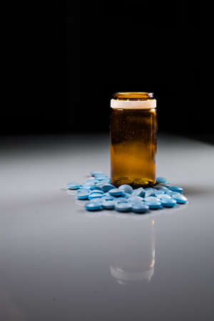 medicine bottle with blue pills on a black background. High quality photoの写真素材