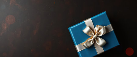 A beautifully wrapped gift box with a teal cover and a gold ribbon sits on a dark background. Perfect for celebrations and gifting.の素材