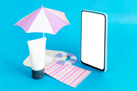 Assembling the skin care cream bottle container, beach umbrella and smart phone on light blue...