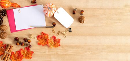 Autumn maple leaves over wooden background, greeting and pen.の写真素材