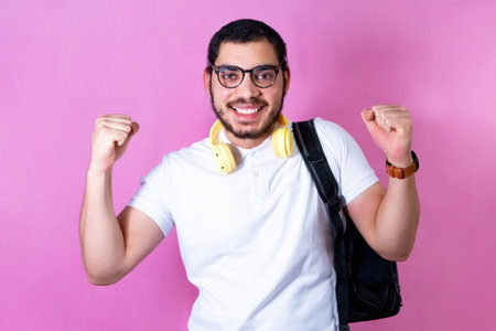 Satisfied and successful young student on pink background. University concept.の写真素材
