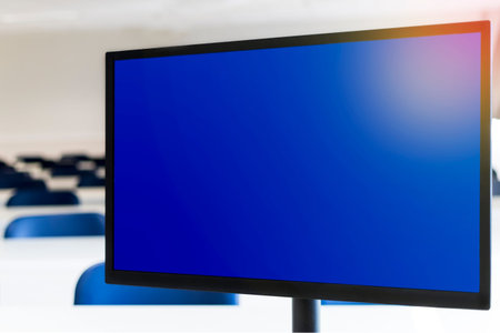 Computer monitor with blue screen, empty classroom in the background. Distance learning concept.の写真素材