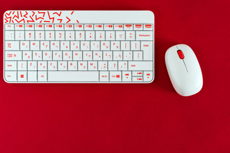 white keyboard and mouse, on red background, with notebook and pen.の写真素材
