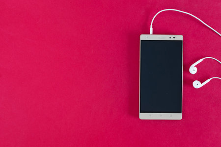 cell phone and headphones, on red background.の写真素材