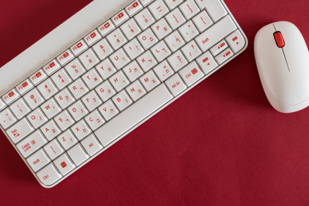 white keyboard and mouse, on red background, with notebook and pen.の写真素材