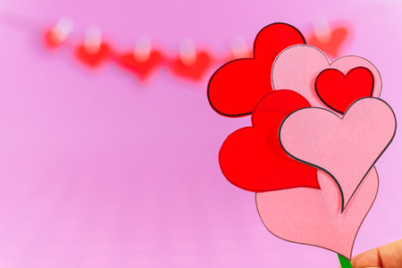 Red love hearts and female hands with bouquet of little hearts on pink background. Valentines day card concept. Heart for Valentines Day Background. Select focus. Soft focus.の写真素材