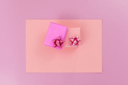 Small gifts wrapped in pink paper, bow ribbon, on pink background. top view. copy textspace.の写真素材