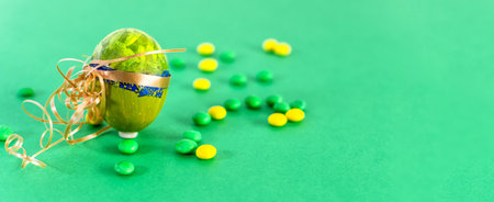 Green Easter egg and candies on a light green background.の写真素材