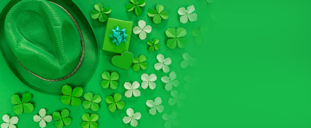 Saint Patrick's day banner with hat, gift, heart and paper clovers. Green background. top view. Copy textspace.の写真素材