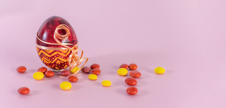 Red Easter egg and candies on a pink background.の写真素材