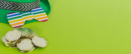 Saint Patrick's Day banner. Green hat, bow tie rainbow figure and golden coins on a green background.の写真素材